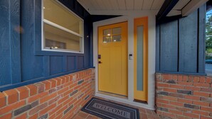 A building entrance with a yellow door, a window, and a brick wall. - Folsom Old Town Escape II - King Bed, A/C, Laundry, Trails, walk to Sutter St (Folsom)