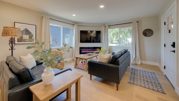 A modern living room with a sofa, a coffee table, a TV, and a large window. - Folsom Old Town Escape II - King Bed, A/C, Laundry, Trails, walk to Sutter St (Folsom)