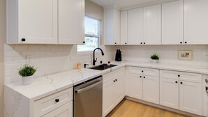 A modern kitchen with white cabinetry, a built-in dishwasher, and a window above the sink. - Folsom Old Town Escape II - King Bed, A/C, Laundry, Trails, walk to Sutter St (Folsom)