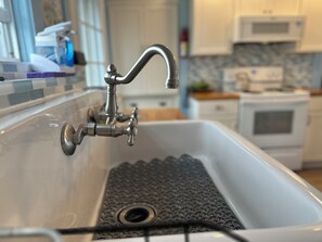 Un lavamanos de cocina con un grifo moderno, un tapón de desagüe y un salpicadero de azulejos.