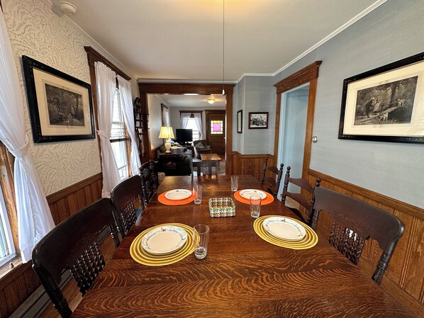 Comedor con una mesa de madera dispuesta para cuatro personas, sillas y una araña.