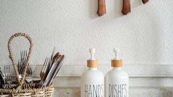 A kitchen with a wooden knife rack, a woven basket with utensils, and two white condiment dispensers labeled "HAND DISHES".