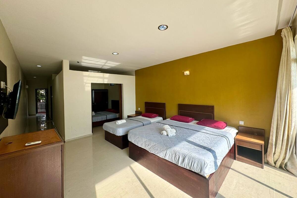 Una camera d'albergo con due letti, una televisione e un armadio in legno.