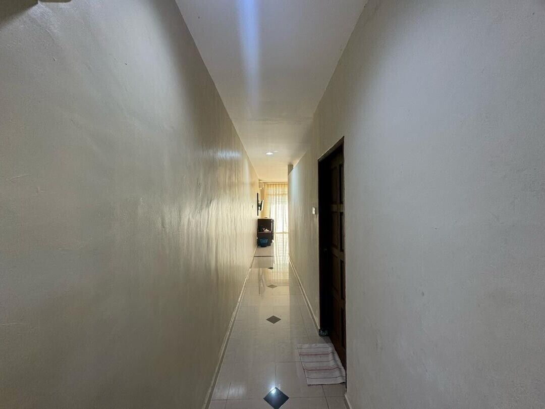 A narrow hallway with white walls and a tiled floor.