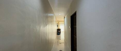 A narrow hallway with white walls and a tiled floor.