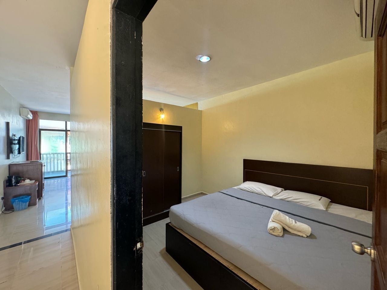 Una habitación de hotel con una cama, un armario, una mesita y una silla.