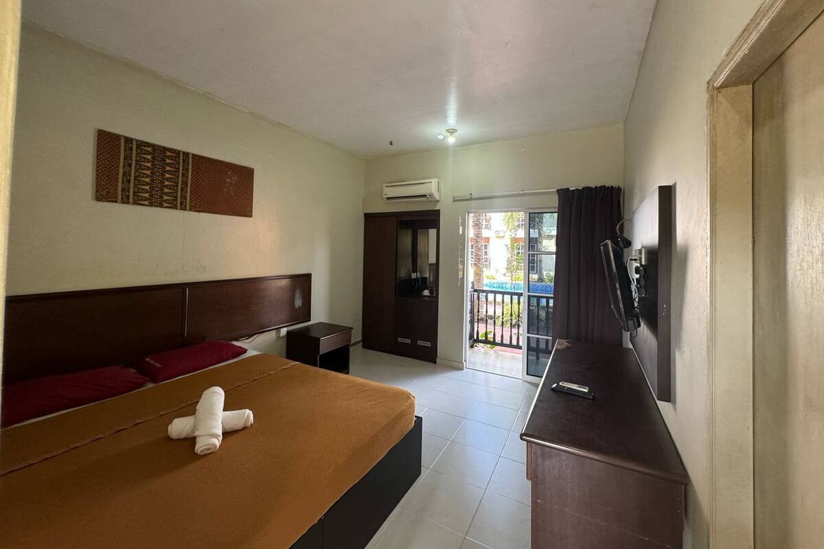 Camera d'albergo con un letto, una scrivania, una TV e una porta scorrevole verso il balcone.