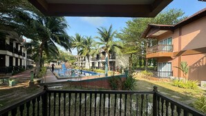 Un patio con piscina, palmeras y un edificio con balcones.