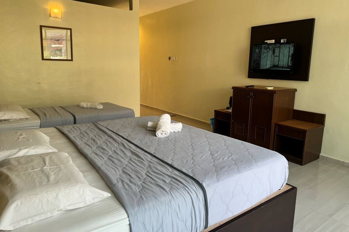 Camera d'albergo con due letti, una TV a parete e un armadio in legno.