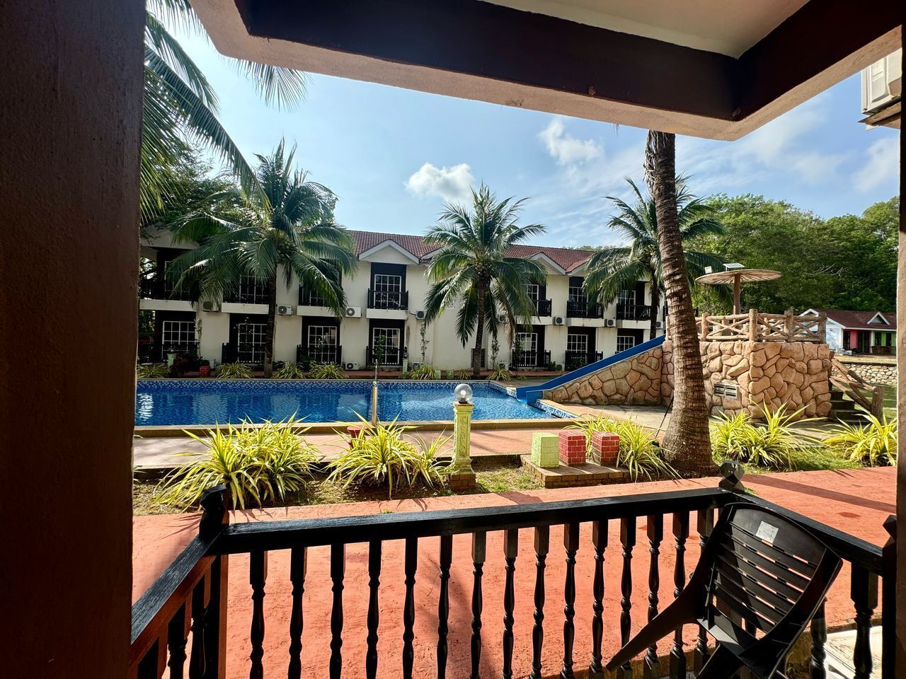 A pool area with a clear view of a building with multiple windows and a stone wall.