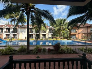Um hotel com piscina, palmeiras e vista para o edifício.