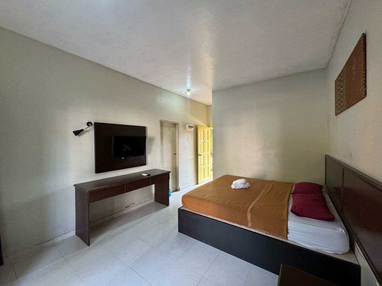 A bedroom with a bed, a desk, a TV, and a window with a view.
