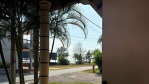 Vista desde un porche con palmeras y una carretera al fondo.