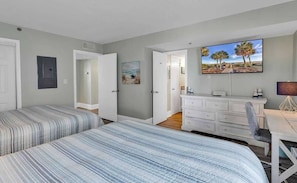 A bedroom with two beds, a dresser, a TV, and a painting on the wall.
