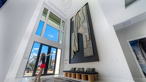 Un interior espacioso con techo alto, ventanas amplias, una obra de arte moderno y una zona de estar con bancos acolchados.