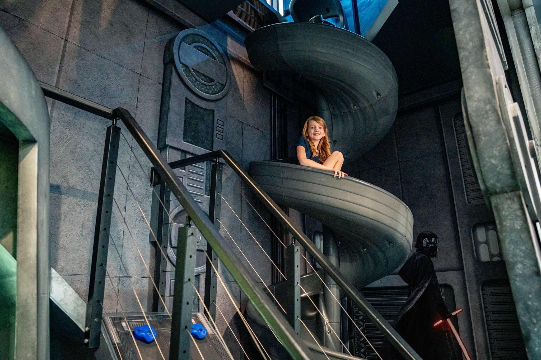 A person on a curved metallic staircase in a futuristic setting with industrial design elements.