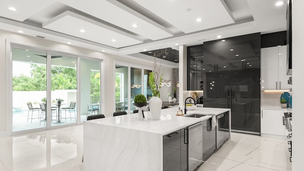 Una cocina moderna con una isla grande, puertas de cristal y vistas al exterior.