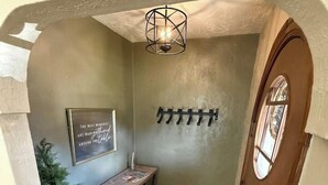 A hallway with a wooden desk, a wall-mounted coat rack, and a door with a window.