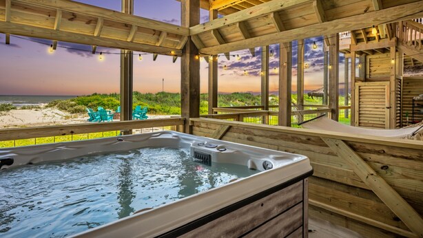 Eine Holterrasse mit Whirlpool, mit Blick auf einen Strand.