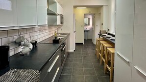 A modern kitchen with white cabinets, a black countertop, and a tiled floor. - 4-bed 3 Bath House in Leicester City (Leicester)