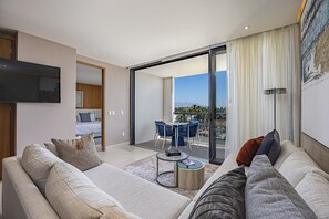 Relax in a spacious living room with a comfortable sofa set, flat-screen TV, and sliding glass door leading to a balcony with a dining area.