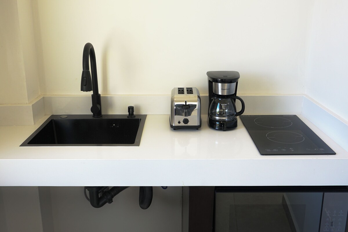 A kitchen with a black sink, a toaster, a coffee maker, and an induction cooktop.
