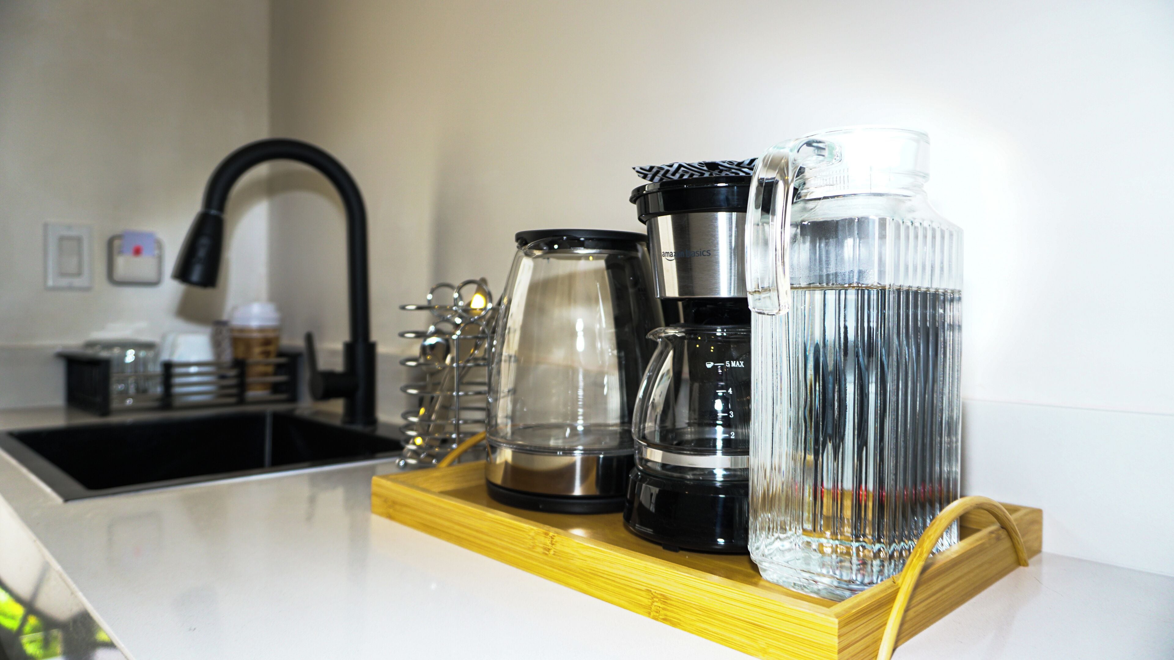 A kitchen counter with a coffee maker, a water dispenser, and a kettle.