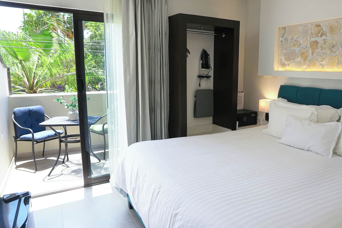 Ein Hotelzimmer mit einem großen Bett, Blick ins Freie, einem kleinen Tisch mit Stuhl und einer Duschkabine.