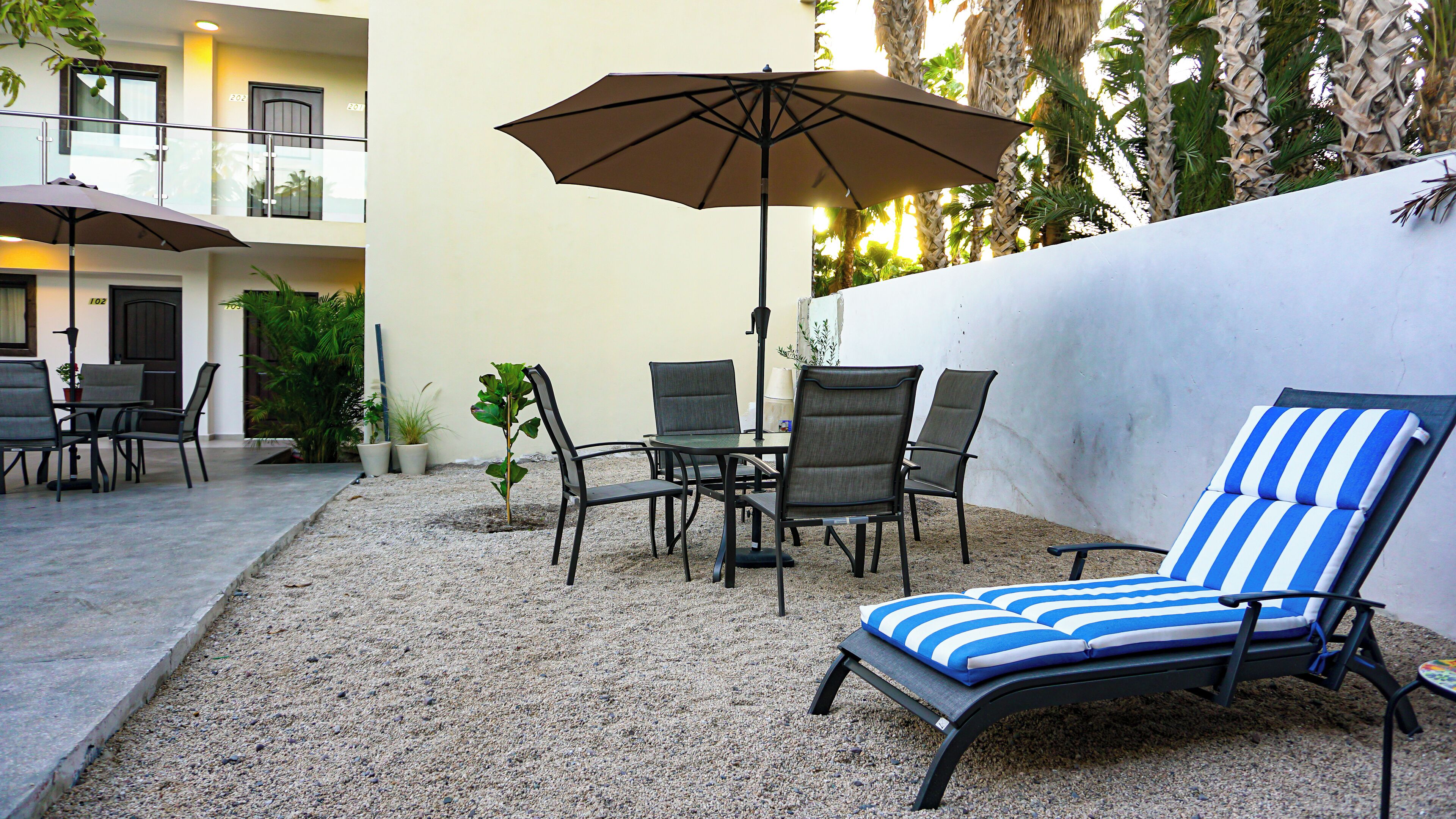 Un espace patio comprenant un fauteuil de relaxation, une table, des chaises et un parasol.