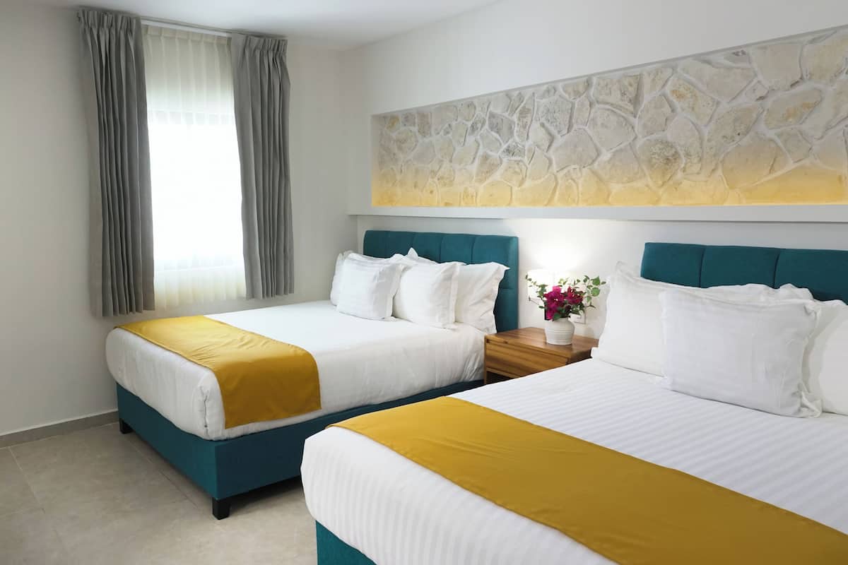 Ein Hotelzimmer mit zwei Betten, einem Nachttisch, einem Fenster mit Vorhängen und einer Wanddekoration.