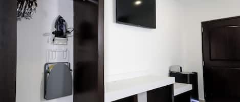 A modern bathroom with a white vanity, a mounted TV, and a dark wooden door.