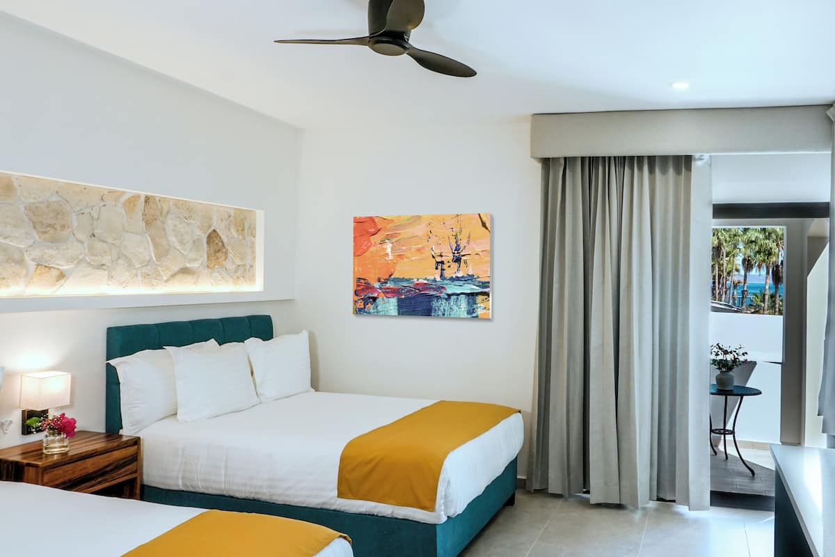Ein Hotelzimmer mit Bett, Deckenventilator, einem Gemälde und Blick ins Freie.