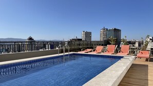 A rooftop pool with clear blue water, surrounded by lounge chairs and a wooden deck. - Ycp-studio613 in S o Paulo (São Paulo)