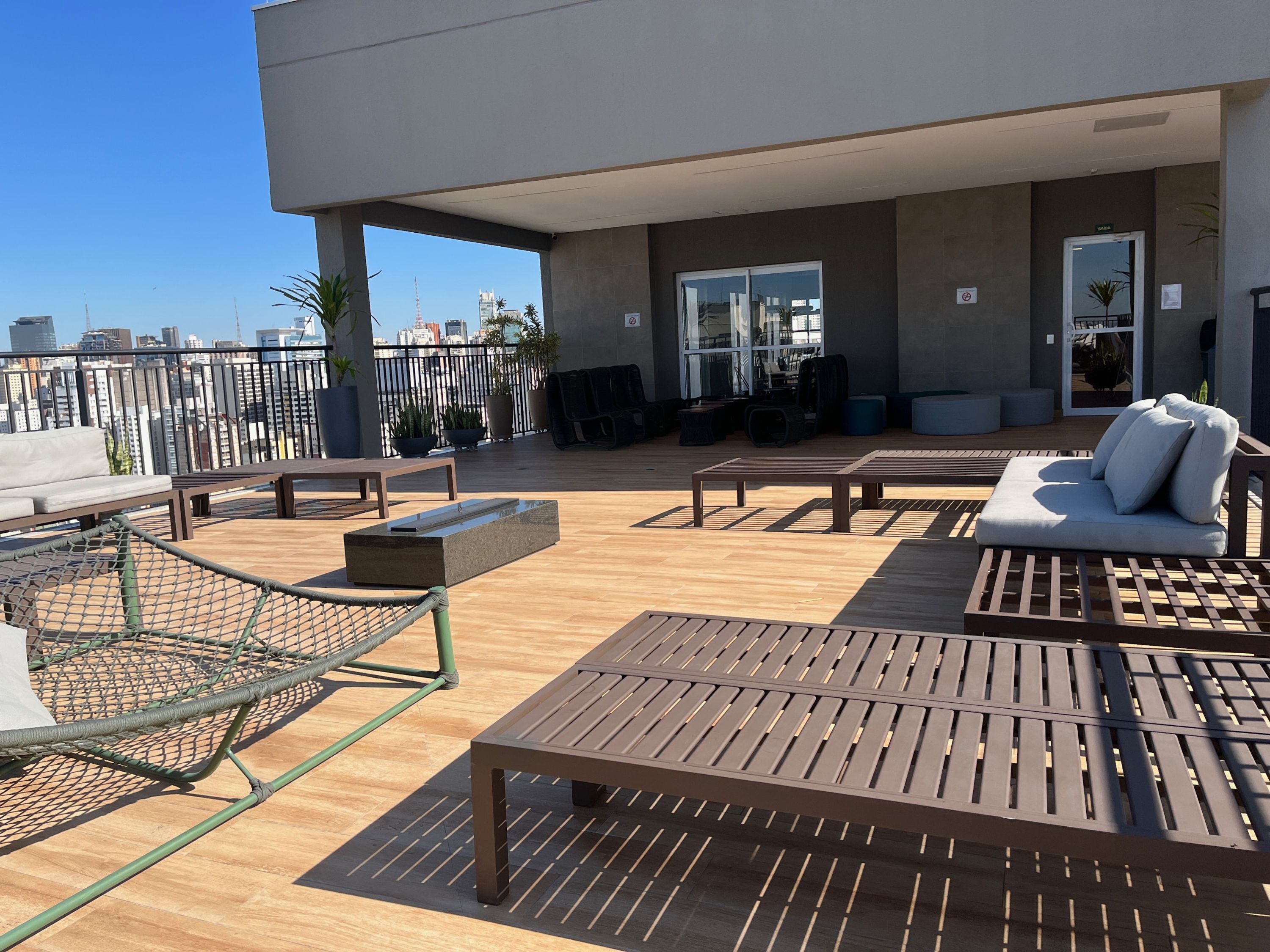 Une terrasse sur le toit, aménagée avec des meubles en bois, un hamac et des plantes en pot.