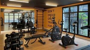 A gym with various exercise equipment, a motivational quote on the wall, and large windows offering a view of the outdoors. - Ycp-studio613 in S o Paulo (São Paulo)