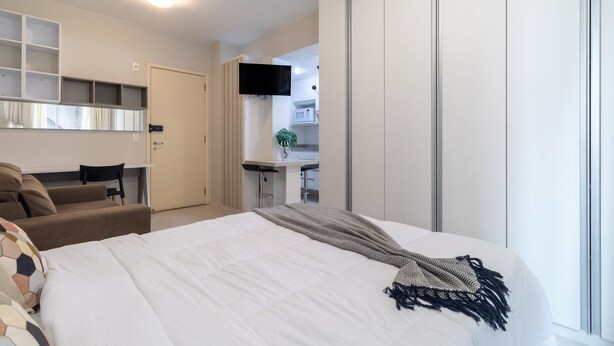 Une chambre d’hôtel comprenant un lit, un bureau, une chaise, une télévision et une armoire.