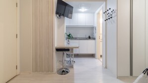 Une cuisine moderne avec des meubles blancs, un téléviseur encastré et un coin bar avec des tabourets.