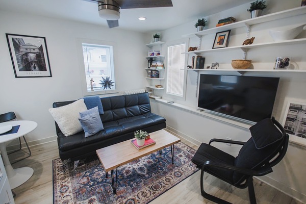 Bright and comfy living room with leather futon, books, games, and 55" smart TV