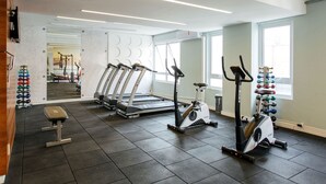 Une salle de sport équipée de tapis de course, d’un appareil elliptique, d’un banc de musculation et d’haltères.