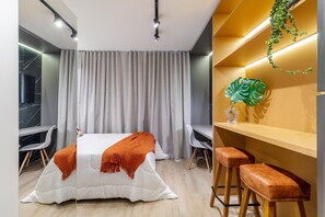 Una camera d'albergo moderna con un letto, due poltrone, una scrivania e un angolo bar.
