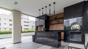 A modern reception area with a black marble counter, wooden shelves, hanging pendant lights, and a view of a building in the background. - Alle 320 in S o Paulo (São Paulo)