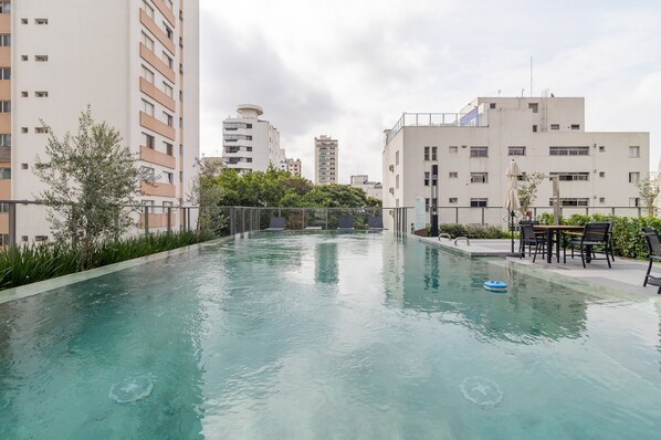 Una piscina con vista chiara sugli edifici circostanti, un tavolo con sedie e un piccolo giocattolo gonfiabile.