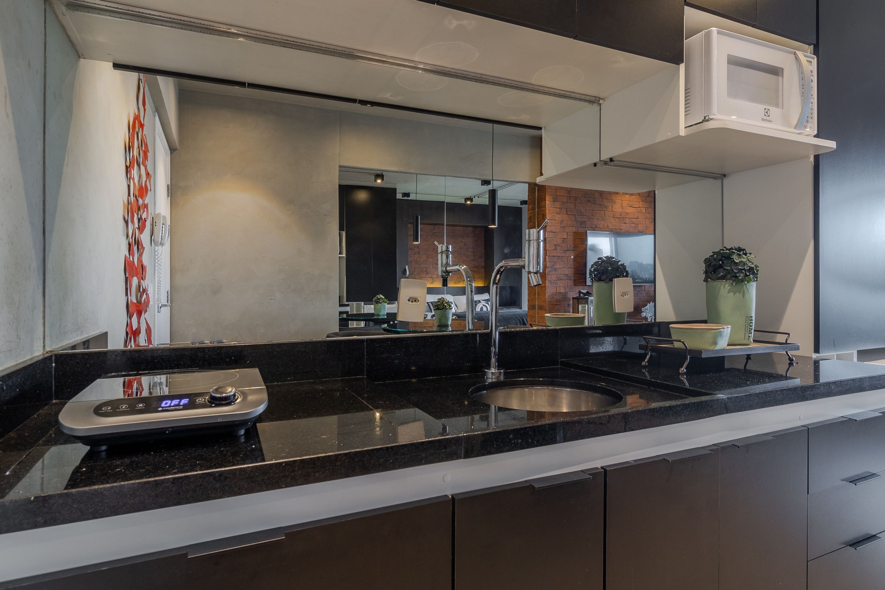 A modern kitchen with a black countertop, stainless steel sink, and a built-in microwave.