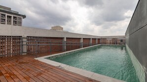 A rooftop swimming pool with a wooden deck and a metal fence. - Mingodoy in S o Paulo (São Paulo)