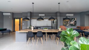 A modern kitchen with a central island, black pendant lighting, and a seating area with sofas and a coffee table. - Mingodoy in S o Paulo (São Paulo)