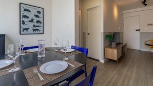 A dining area with a black table set for four, blue chairs, and a framed cat-themed artwork on the wall. - Machado 238 Ap 137 in S o Paulo (São Paulo)