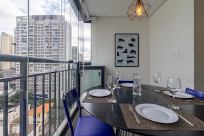 A dining area with a table set for four, a city view through large windows, and a framed poster on the wall. - Machado 238 Ap 137 in S o Paulo (São Paulo)