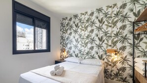A hotel room with a bed, a nightstand, a wooden bench, and a window with a view of buildings. - Machado 238 Ap 137 in S o Paulo (São Paulo)