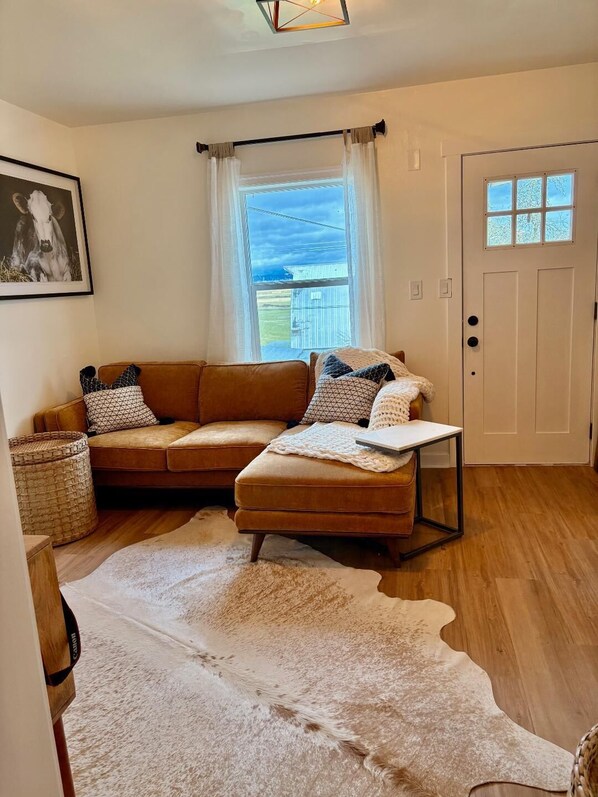 A cozy living room with a brown sectional sofa, a white rug, and a small table.