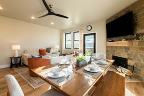 A dining area with a wooden table set for four, a fireplace, and a stone wall. - DVEV Condo-Year Round Activities-Communal Amenities-Free Ski Shuttle (Heber City)